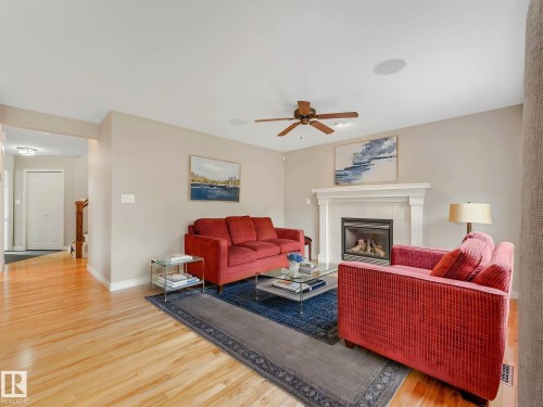 Living room featuring wood-finish flooring, a fireplace with a white mantel, and light-toned walls - 1325 Latta Crescent, Edmonton, AB - Indoor Photo Showing Living Room With Fireplace