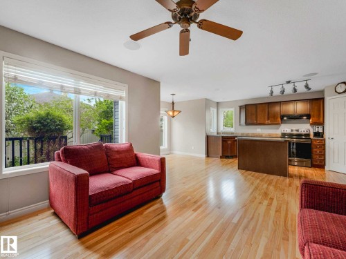 Open-concept living space featuring wood-finish flooring, a ceiling fan, and large windows with outdoor scenery - 1325 Latta Crescent, Edmonton, AB - Indoor