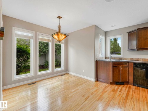 Dining area with wood-finish flooring, ample natural light through multiple windows, and a decorative ceiling fixture - 1325 Latta Crescent, Edmonton, AB - Indoor Photo Showing Other Room