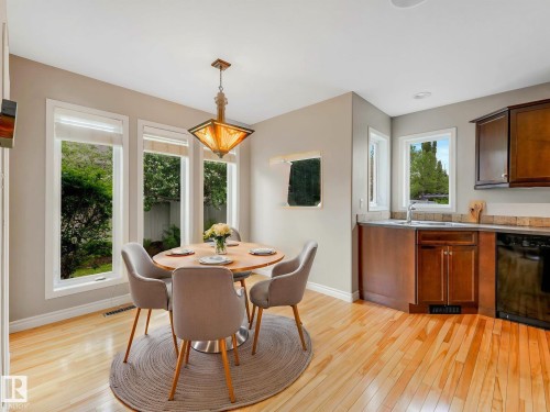 Dining area featuring wood-finish flooring, a contemporary pendant light fixture, and three large windows - 1325 Latta Crescent, Edmonton, AB - Indoor Photo Showing Dining Room