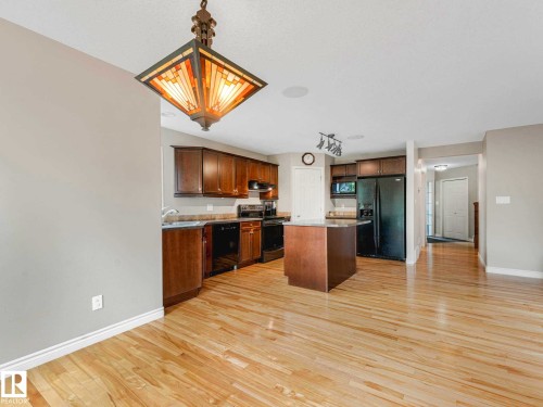 Kitchen with wood-finish flooring, dark wood cabinetry, and a central island - 1325 Latta Crescent, Edmonton, AB - Indoor Photo Showing Kitchen