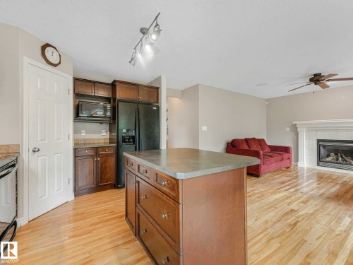 Kitchen island featuring a solid surface countertop and wood-finish cabinetry - 1325 Latta Crescent, Edmonton, AB - Indoor Photo Showing Kitchen With Fireplace