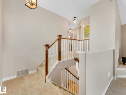 Staircase with carpeted treads and risers, featuring wood newel posts and handrails, and white balusters - 1325 Latta Crescent, Edmonton, AB - Indoor Photo Showing Other Room