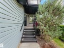 Exterior entry featuring light blue horizontal siding, dark grey stairs with non-slip treads, a black handrail, and a covered porch area - 1325 Latta Crescent, Edmonton, AB  - Outdoor 