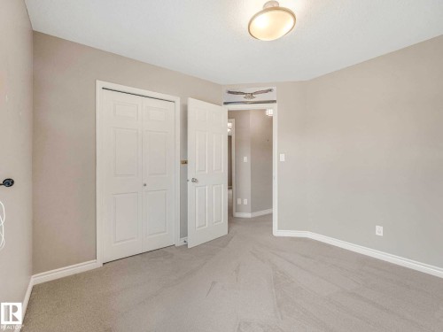 Carpeted room featuring a double-door closet, neutral wall paint, white trim, a flush-mount ceiling light, and a white interior door - 1325 Latta Crescent, Edmonton, AB - Indoor Photo Showing Other Room
