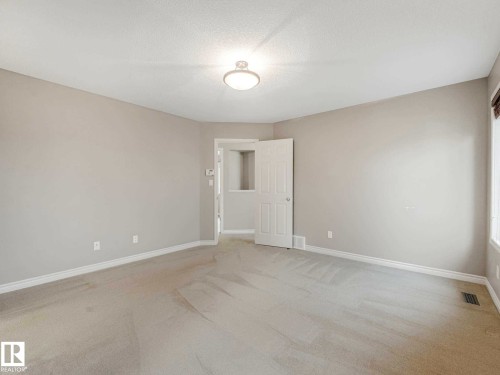 Spacious room featuring neutral carpeting, light-toned walls, white trim, a flush-mount ceiling light, and a white paneled door - 1325 Latta Crescent, Edmonton, AB - Indoor Photo Showing Other Room