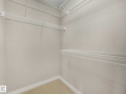 Walk-in closet featuring light gray walls, white wire shelving, white baseboards, and carpeted flooring - 1325 Latta Crescent, Edmonton, AB - Indoor With Storage