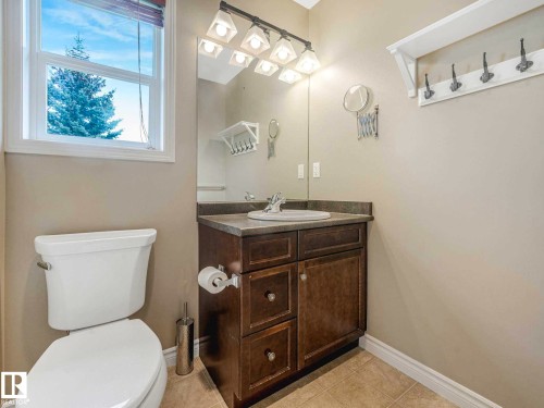 Bathroom featuring a single window, a dark wood-finish vanity with an integrated sink, a large mirror, and a wall-mounted light fixture with four sconces - 1325 Latta Crescent, Edmonton, AB - Indoor Photo Showing Bathroom