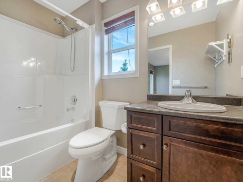 Bathroom featuring a white shower-tub combination, dark wood-finish vanity with a light countertop, a white toilet, and tile flooring - 1325 Latta Crescent, Edmonton, AB - Indoor Photo Showing Bathroom