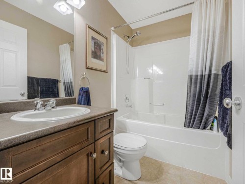 Bathroom featuring a vanity with a laminate countertop, an undermount sink, and a wood-finish cabinet - 1325 Latta Crescent, Edmonton, AB - Indoor Photo Showing Bathroom