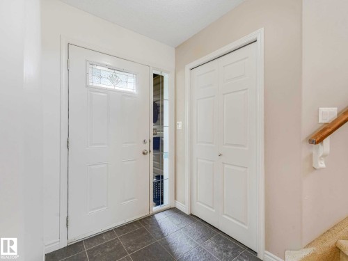 Entryway featuring tile flooring, a front door with decorative glass inlay, an adjacent sidelight, and a bi-fold closet - 1325 Latta Crescent, Edmonton, AB - Indoor Photo Showing Other Room