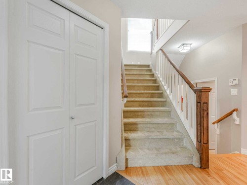 Carpeted staircase with wood railing and white balusters - 1325 Latta Crescent, Edmonton, AB - Indoor Photo Showing Other Room