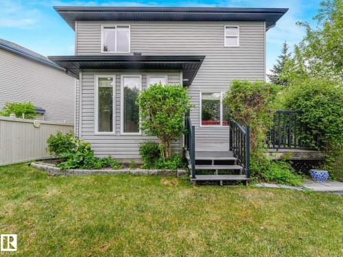 Rear exterior featuring gray horizontal siding, multiple windows, and a raised wooden deck with railings - 1325 Latta Crescent, Edmonton, AB - Outdoor