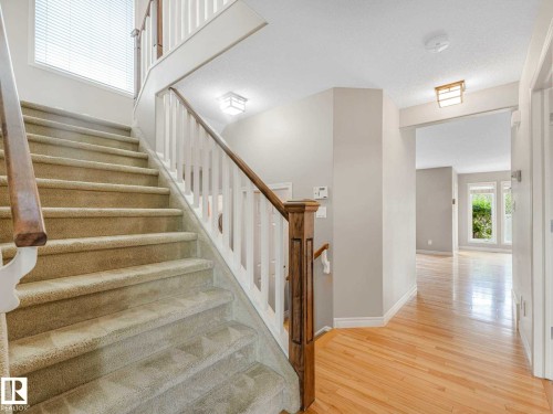 Curved staircase with carpeted treads and white risers, featuring a wood handrail and white balusters - 1325 Latta Crescent, Edmonton, AB - Indoor Photo Showing Other Room
