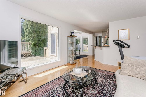 Spacious living area featuring hard surface flooring, a large picture window, and a built-in breakfast bar - 11023 11A Avenue, Edmonton, AB 