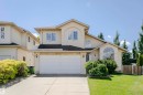 Stucco exterior featuring a dual-car garage, concrete driveway, arched window, and mature landscaping - 11023 11A Avenue, Edmonton, AB 