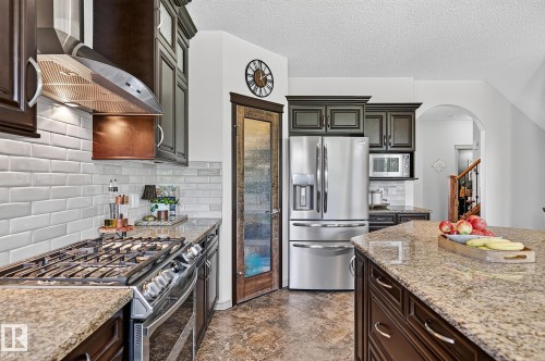 Well-appointed kitchen featuring granite countertops, stainless steel appliances, dark wood cabinetry, white subway tile backsplash, and a central island - 163 Galland Crescent, Edmonton, AB 
