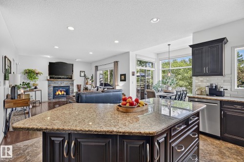 Central kitchen island with granite countertop, dark wood cabinetry, and recessed lighting throughout - 163 Galland Crescent, Edmonton, AB 