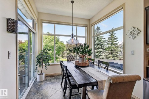Dining area featuring expansive windows, a sliding glass door, a contemporary pendant light fixture, and dark tile flooring - 163 Galland Crescent, Edmonton, AB 
