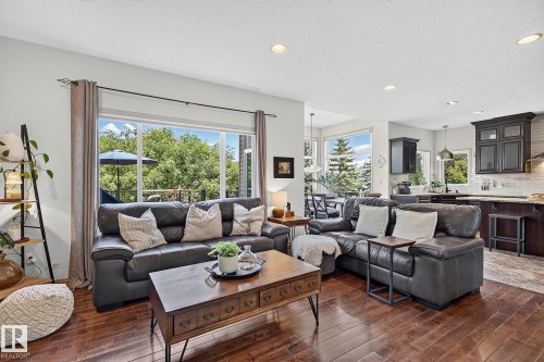 Open-concept living space featuring wood-finish flooring, recessed lighting, and expansive windows - 163 Galland Crescent, Edmonton, AB 
