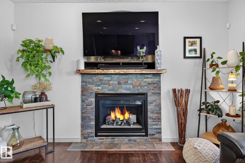 Stacked stone fireplace with a natural wood mantel - 163 Galland Crescent, Edmonton, AB 