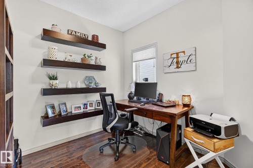 Dedicated workspace featuring wood-finish flooring, built-in floating shelving, and a window with blinds - 163 Galland Crescent, Edmonton, AB 