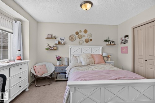 Carpeted room featuring a window with blinds, a built-in closet with double doors, and a ceiling-mounted light fixture - 163 Galland Crescent, Edmonton, AB 