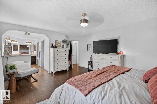 Spacious room featuring wood-finish flooring, a ceiling fan with integrated lighting, and an arched entryway - 163 Galland Crescent, Edmonton, AB 