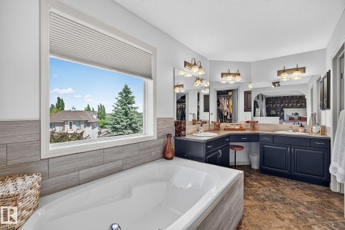 Soaking tub with a window view, complemented by wood-finish flooring - 163 Galland Crescent, Edmonton, AB 