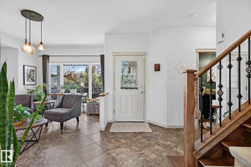 Entryway featuring an ornate glass-paneled door, tile flooring, and a wood staircase with decorative iron spindles - 163 Galland Crescent, Edmonton, AB 