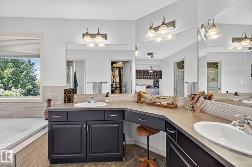 Dual vanity with black cabinetry, integrated sinks, and neutral countertops - 163 Galland Crescent, Edmonton, AB 