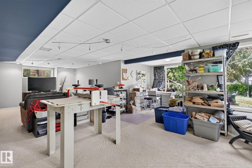 Spacious lower-level room featuring light carpet flooring and a suspended ceiling with track lighting - 163 Galland Crescent, Edmonton, AB 