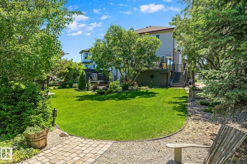 Expansive backyard featuring a manicured lawn, established trees, and a multi-level deck with stairs - 163 Galland Crescent, Edmonton, AB 