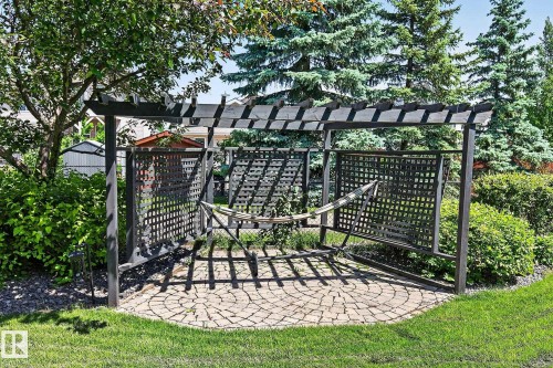 Dedicated outdoor sitting area featuring a dark-stained pergola, decorative lattice panels, and a circular paver patio - 163 Galland Crescent, Edmonton, AB 