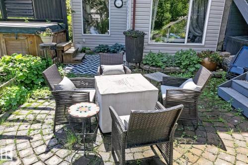 Stone paver patio featuring a hot tub, cultivated garden beds, and gray vinyl siding - 163 Galland Crescent, Edmonton, AB 