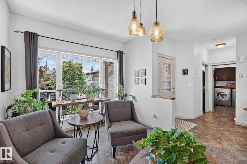 Living area with large picture windows and multiple pendant light fixtures - 163 Galland Crescent, Edmonton, AB 