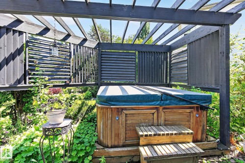 Hot tub enclosure featuring a dark-stained wood pergola and slatted privacy screens - 163 Galland Crescent, Edmonton, AB 