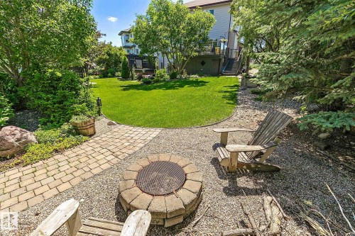 Landscaped backyard featuring a stone fire pit, gravel patio area, and a paver pathway - 163 Galland Crescent, Edmonton, AB 