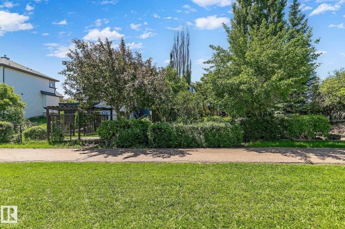 Expansive green space featuring a paved pathway, mature trees, and sculpted hedges - 163 Galland Crescent, Edmonton, AB 