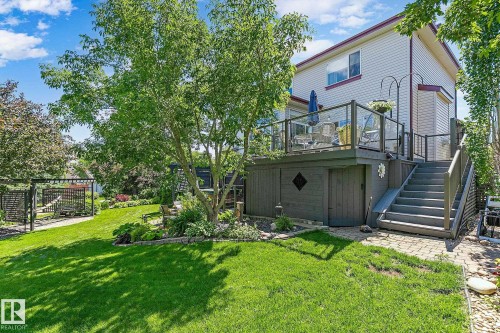 Expansive backyard featuring a multi-level deck with glass panel railing, a set of exterior stairs, and a lower-level storage area - 163 Galland Crescent, Edmonton, AB 