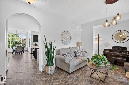 Arched doorway leading to a dining area with large windows, dark cabinetry, and tile flooring - 163 Galland Crescent, Edmonton, AB 