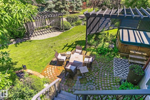 Tiered backyard featuring a manicured lawn, two pergolas, and a hot tub deck - 163 Galland Crescent, Edmonton, AB 