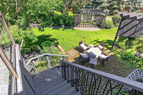 Multi-level outdoor living space featuring a paver patio with a dining area, a lush lawn, and a secondary circular paver area under a pergola - 163 Galland Crescent, Edmonton, AB 
