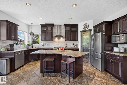 Kitchen featuring dark wood cabinetry, granite countertops, and stainless steel appliances - 163 Galland Crescent, Edmonton, AB 