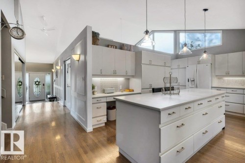 Kitchen featuring a large central island with storage, white cabinetry, integrated appliances, and a tile backsplash - 11742 29 Avenue, Edmonton, AB 