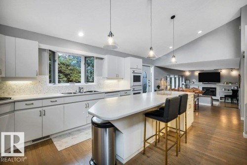Open-concept kitchen featuring an elongated island with seating, integrated wall oven, and a bay window above the sink - 11742 29 Avenue, Edmonton, AB 
