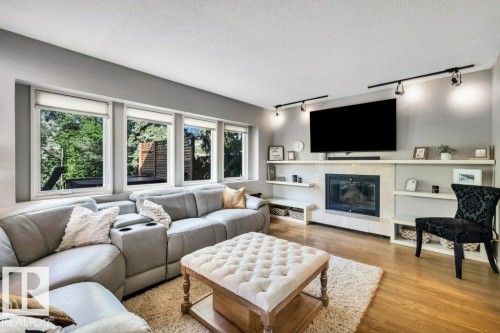 Living area featuring a fireplace with a light-toned surround, integrated shelving, and track lighting - 11742 29 Avenue, Edmonton, AB 