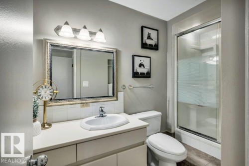Bathroom featuring a single vanity with an integrated sink, framed mirror, and three-light fixture - 11742 29 Avenue, Edmonton, AB 