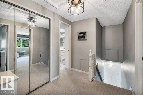 Hallway featuring mirrored closet doors, neutral carpeting, and a contemporary ceiling fixture - 11742 29 Avenue, Edmonton, AB 