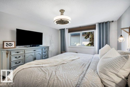 Bedroom featuring a window with a brown blind and blue drapes, a ceiling fan with integrated lighting, and light-colored walls - 11742 29 Avenue, Edmonton, AB 
